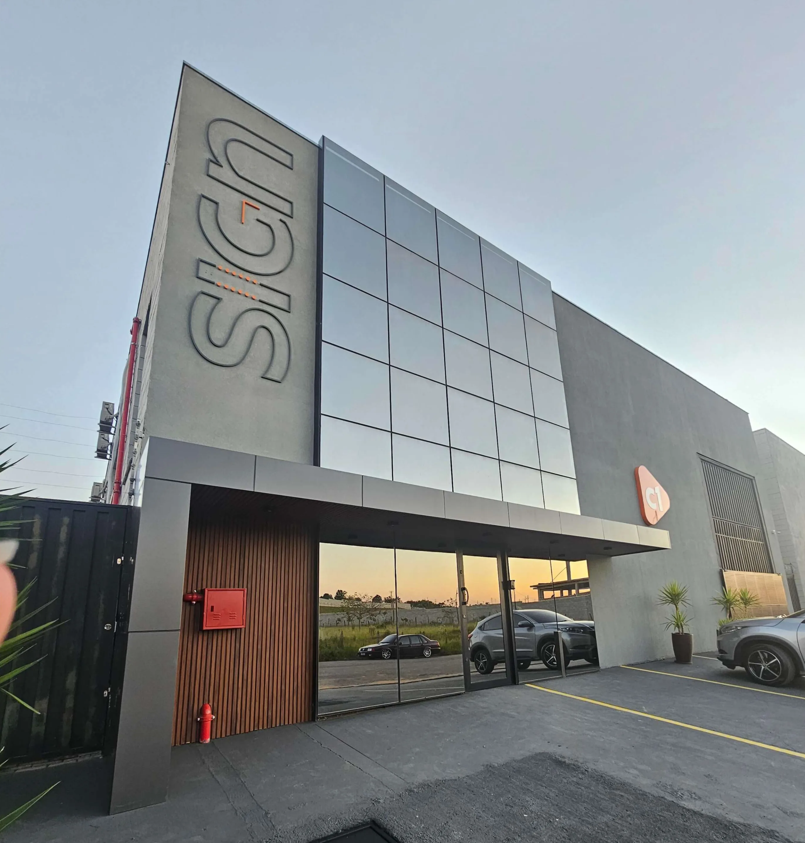 Sede da C1 Sign ao entardecer, com letra caixa 'SIGN' na lateral e ícone C1 na entrada